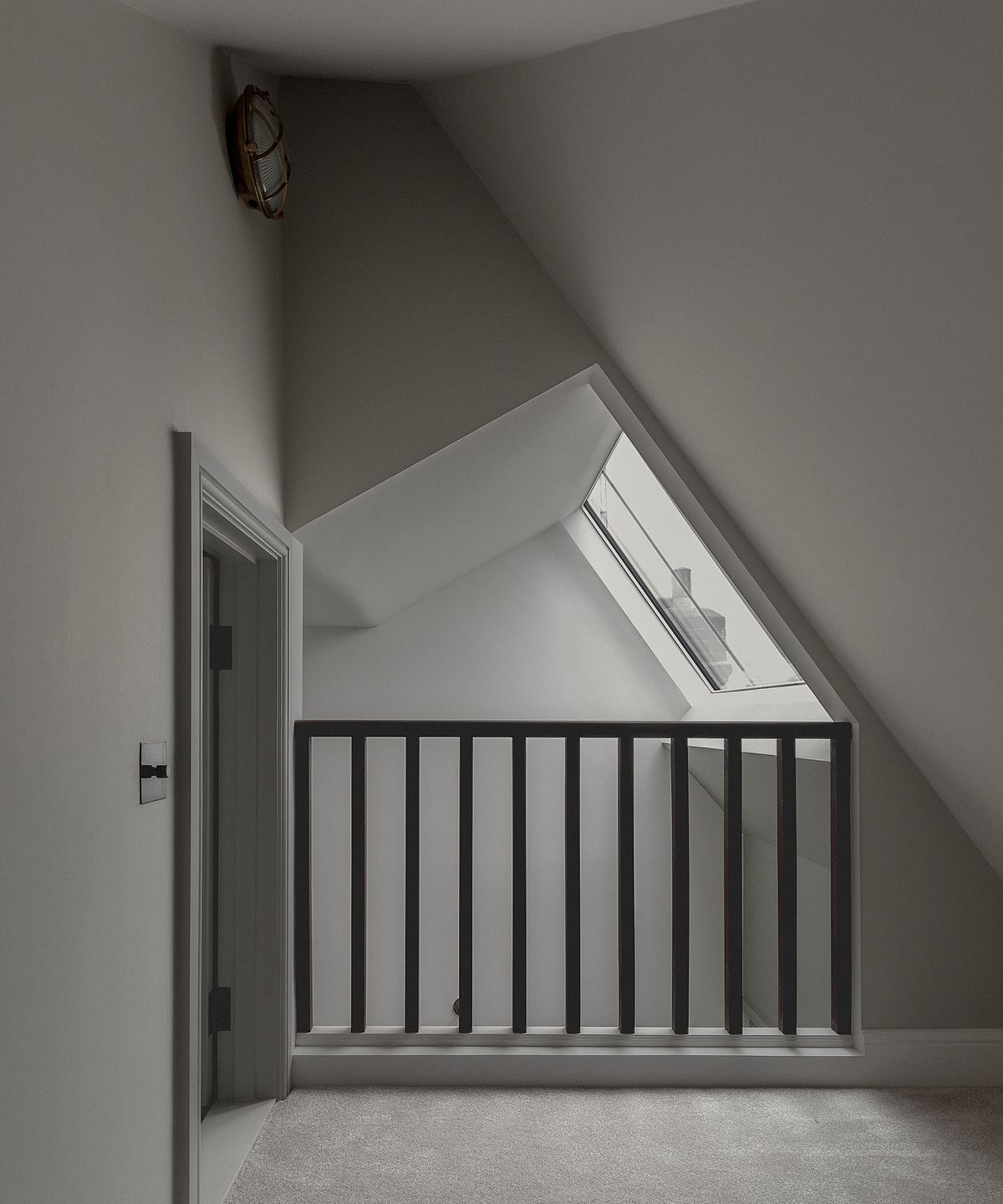 A landing in a loft space painted grey with angled ceilings