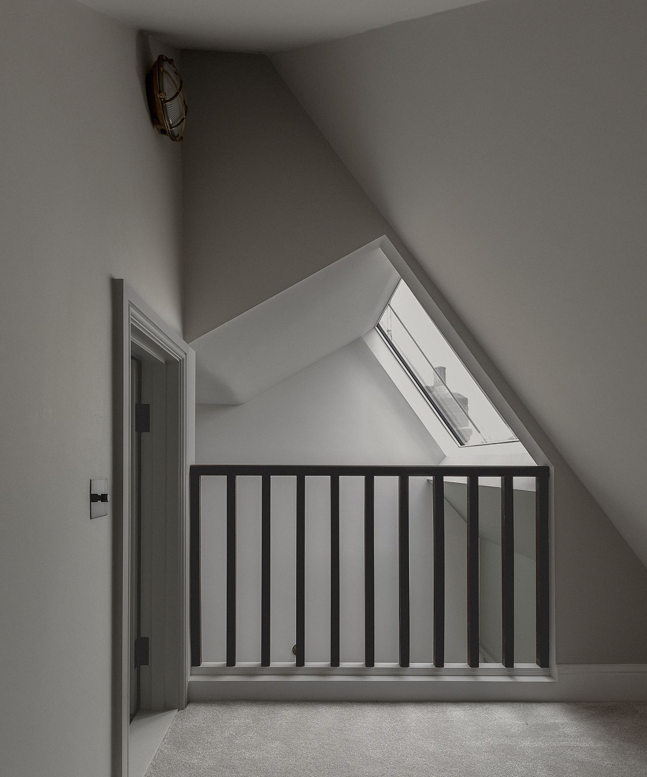 A landing in a loft space painted grey with angled ceilings