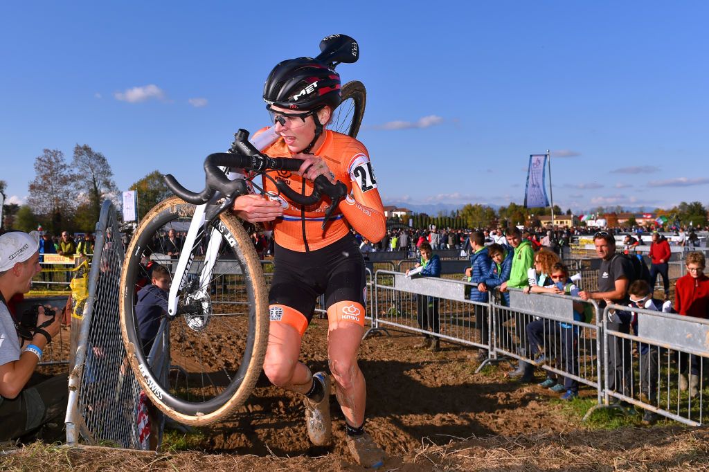 Kastelijn carries her bike over a thick mud section