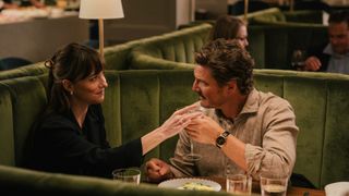 Dakota Johnson and Pedro Pascal sitting in a restaurant booth in Materialists