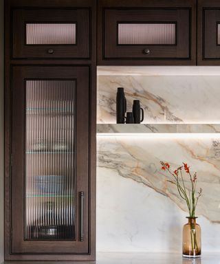 A dark wood kitchen cabinet features reeded glass as a unique detail