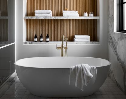 A white bathroom with wood accents and warm hardware