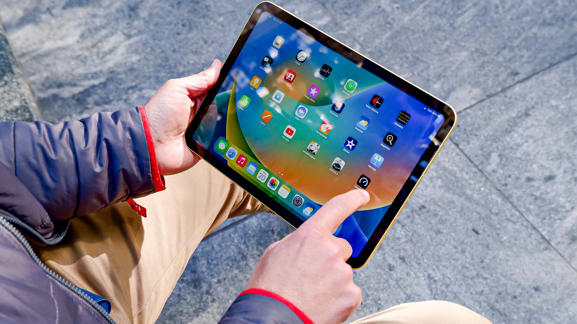 iPad 10th generation in the hands browsing the iPad OS home screen