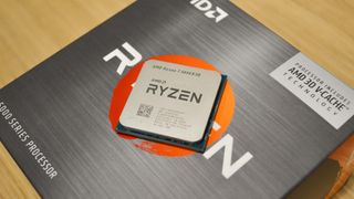En AMD Ryzen 7 5800X3D-processor ligger ovanpå sin tillhörande förpackning på ett träfärgat bord.