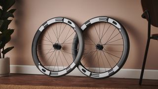 A pair of HED Vanquish RC6 Pro road bike wheels leans against a terracotta wall
