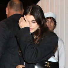 Kaia Gerber wears a black blazer, riding boots, and carries a Celine bag at Billie Eilish's Halloween party