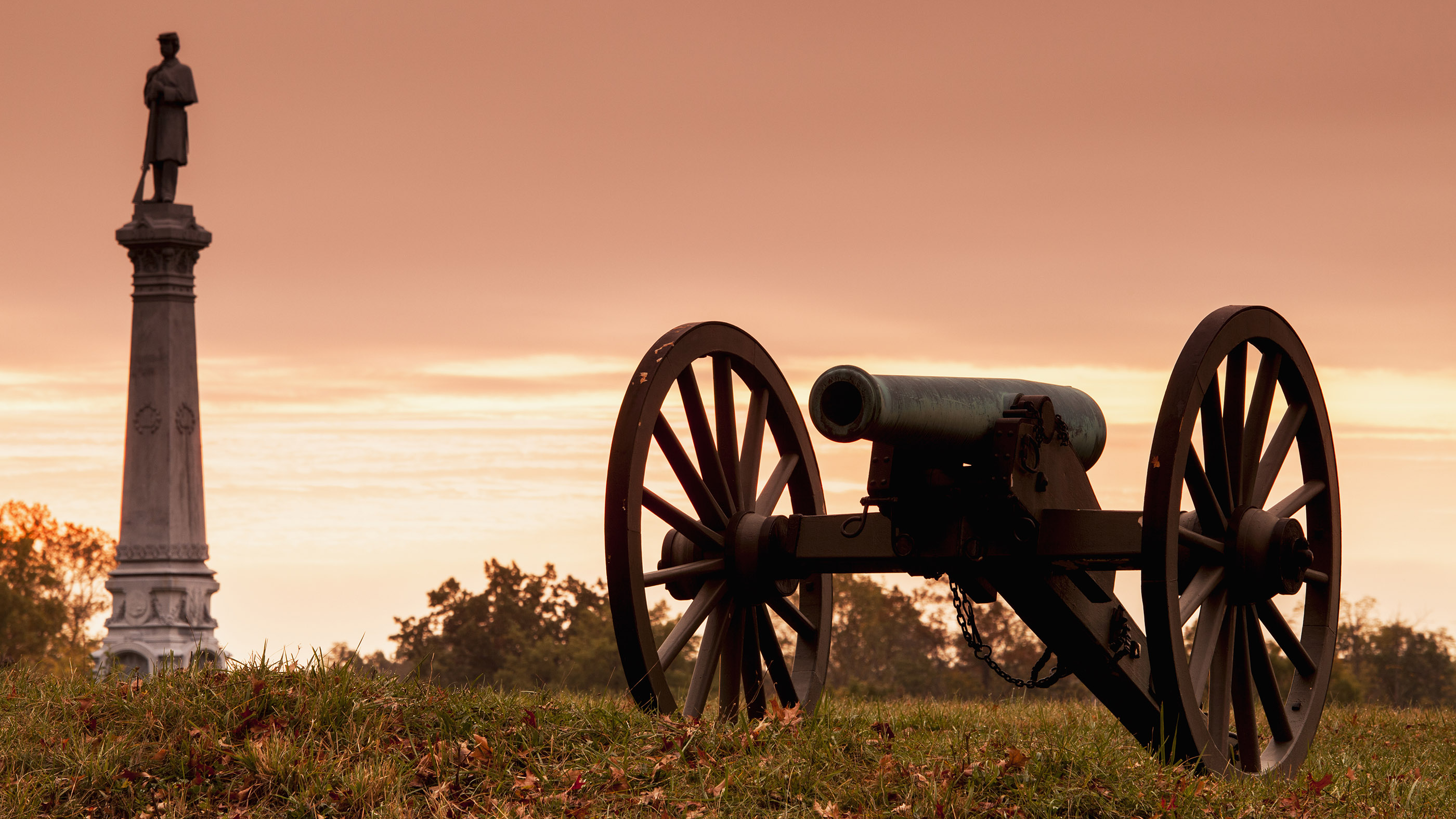 The Battle of Gettysburg, battlefield monument and Civil War cannon shown at dawn.