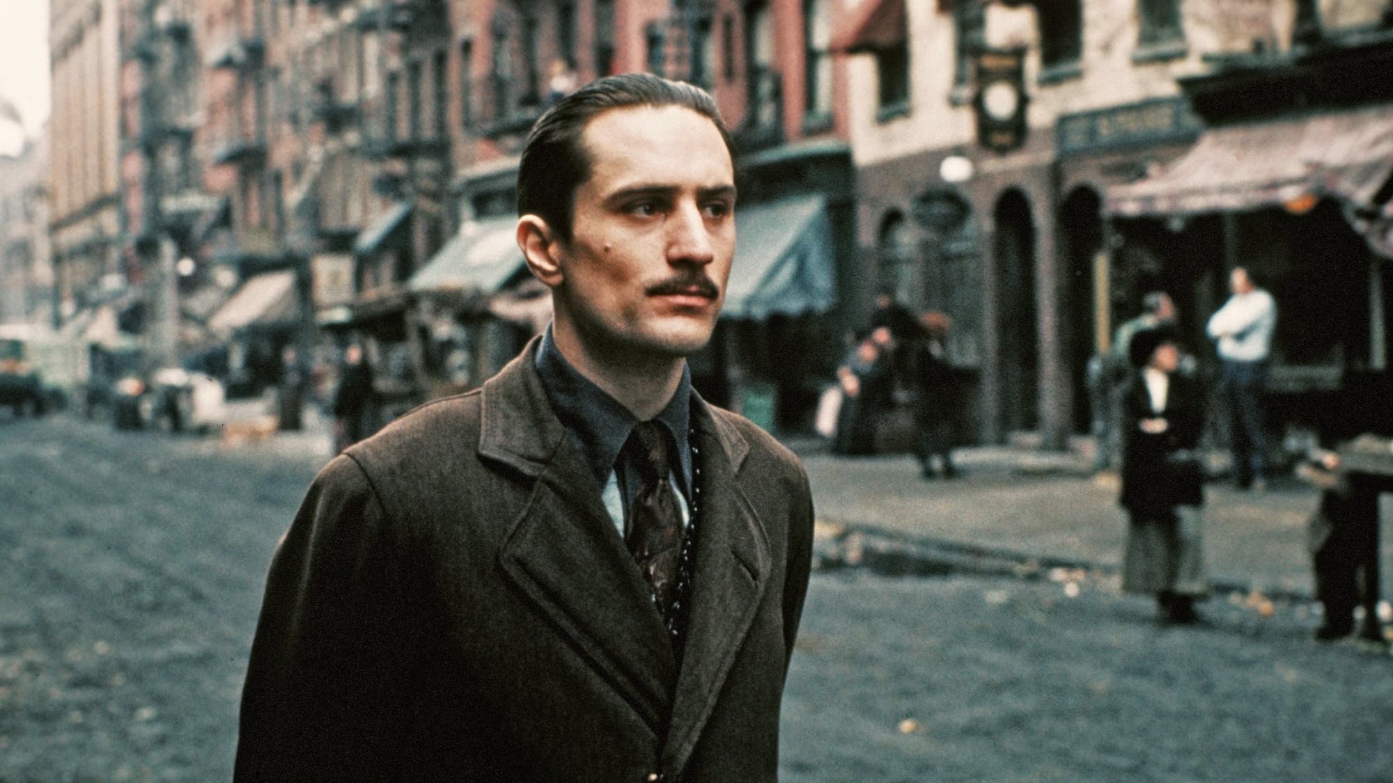 head-on photo of Robert De Niro in a suit on the streets of New York. he is playing a young Vito Corleone in 'The Godfather Part II.'