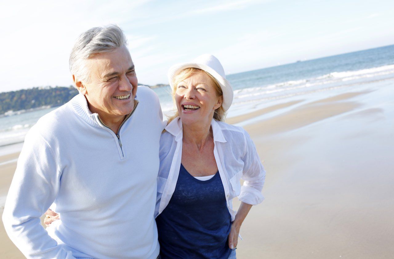 Happy senior couple walking on beach