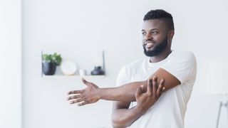 Man stretching arms at home