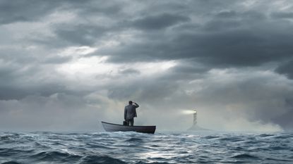 A businessman with a briefcase stands in a boat on rough waters looking toward a lighthouse in the distance.