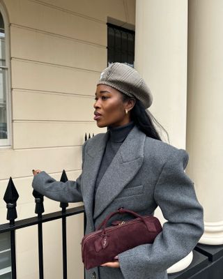 Woman in gray coat and burgundy east-west bag.