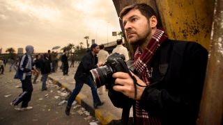 Chris Hondros holds a camera in a busy street