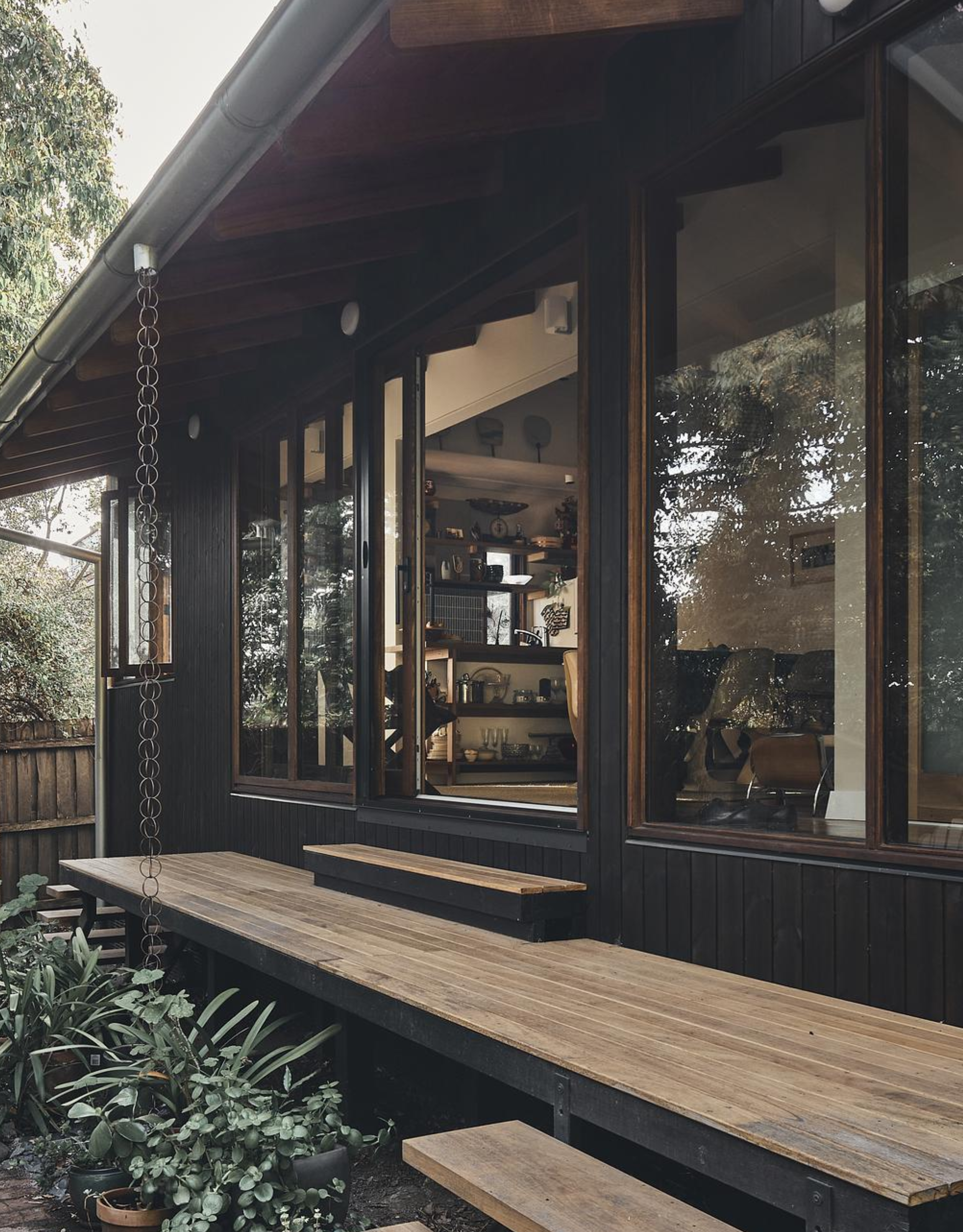 A home with an engawa and a rain chain against a black and wood facade