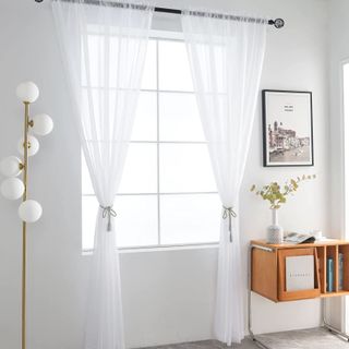 White living room with sheer curtains and wooden side table