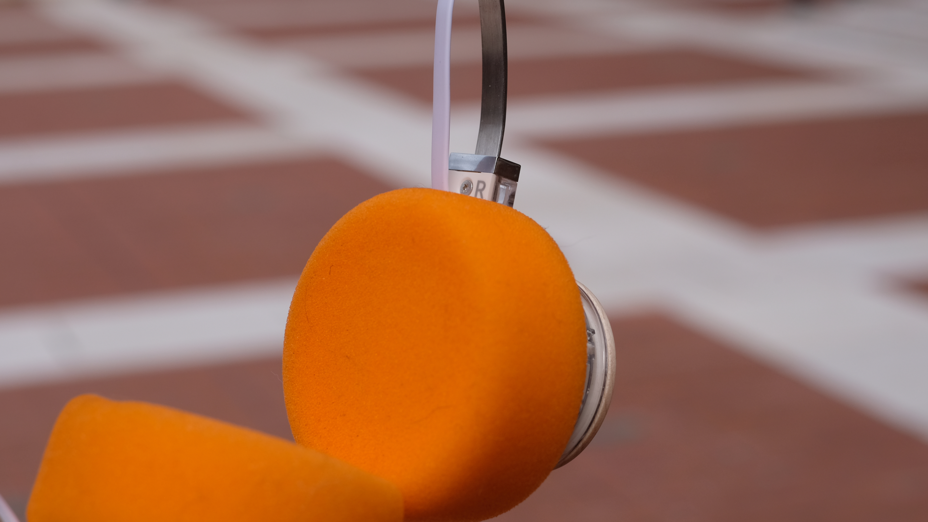 A photograph of the FiiO EH11 over-ear headphones with a transparent frame and orange foam earpads.