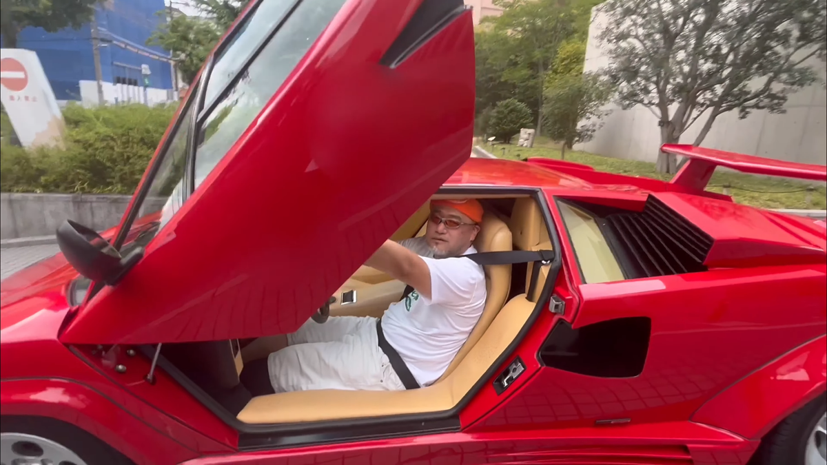 Hideki Kamiya sits in the driver&#039;s seat of a Lamborghini, door open.