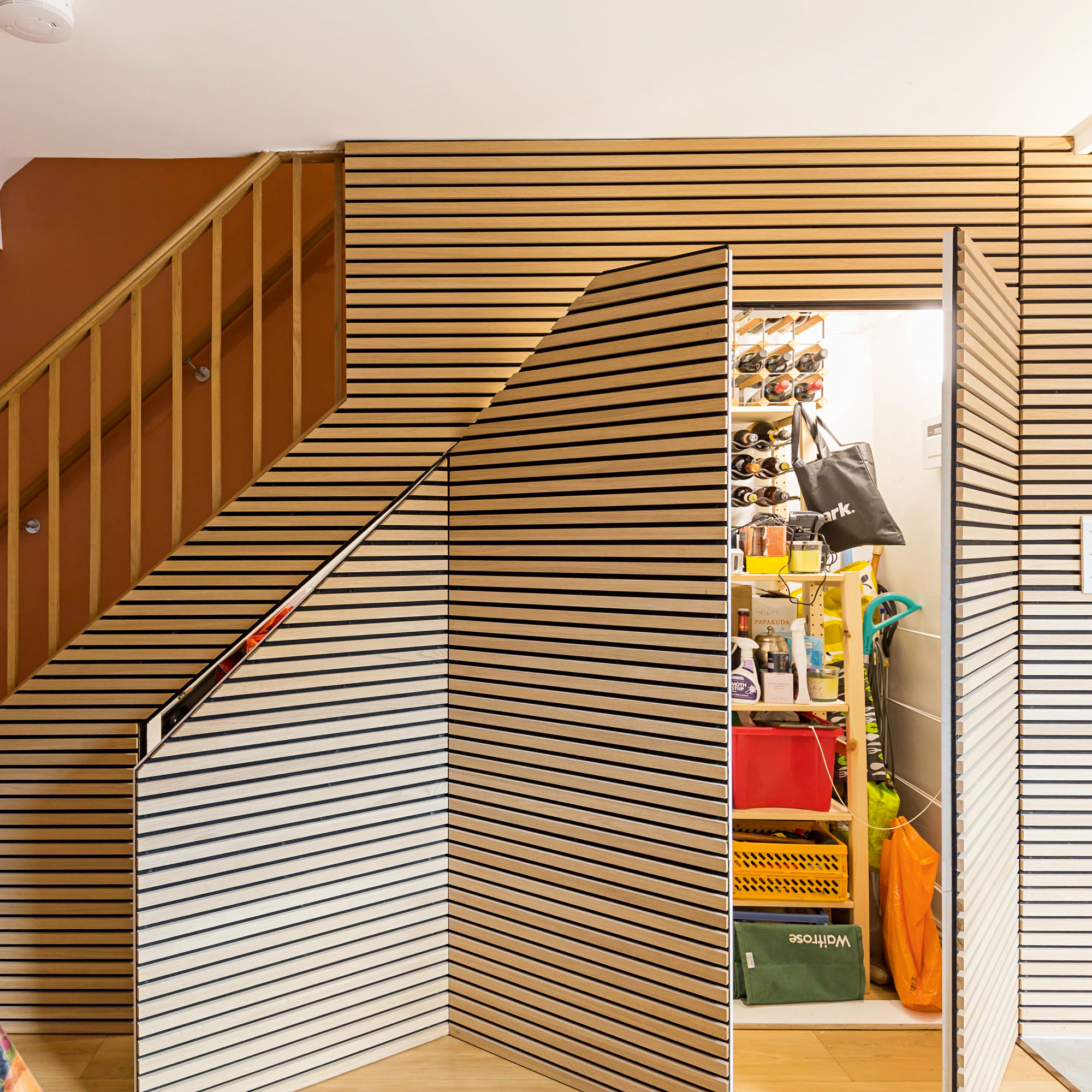 storage cupboards are under the stairs via a hidden doors within the horizontal wood panelling