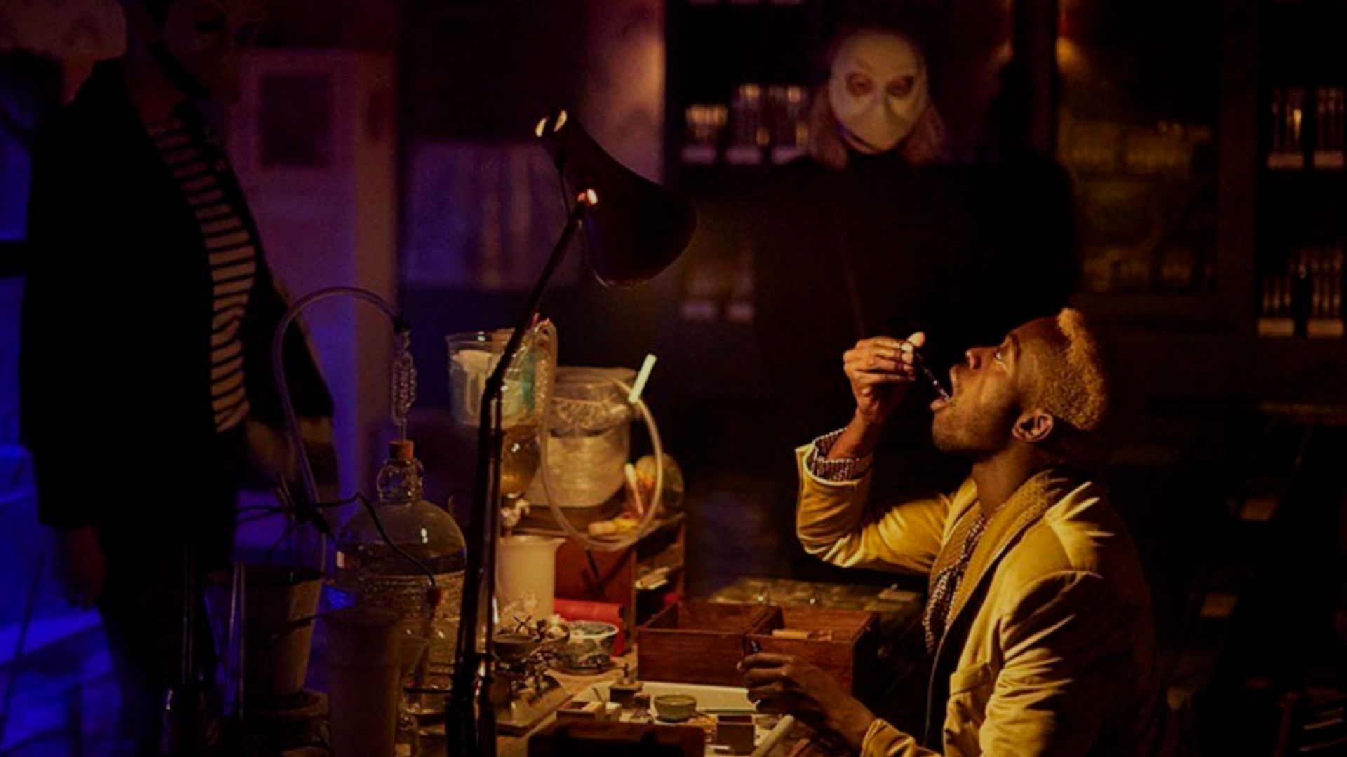 an image from the set of The Burning Man Punchdrunk show, where an actor is concocting and drinking a vial of liquid whilst a member of the audience watches