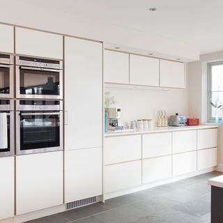A white kitchen with four ovens built into the cupboard space