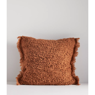 terracotta toned fluffy boucle pillow with fringed border