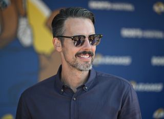 Josh Kroenke smiles in front of a billboard