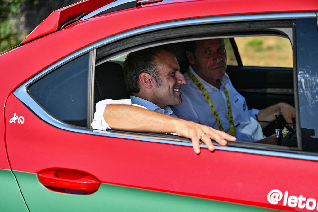 General director of the Tour de France Christian Prudhomme and France's President Emmanuel Macron ride in the race direction vehicle near the ascent of Hautacam during the 12th stage of the 112th edition of the Tour de France cycling race, 180.6 km between Auch and Hautacam, in the Pyrenees mountains of southwestern France, on July 17, 2025. (Photo by Marco BERTORELLO / AFP) (Photo by MARCO BERTORELLO/AFP via Getty Images)