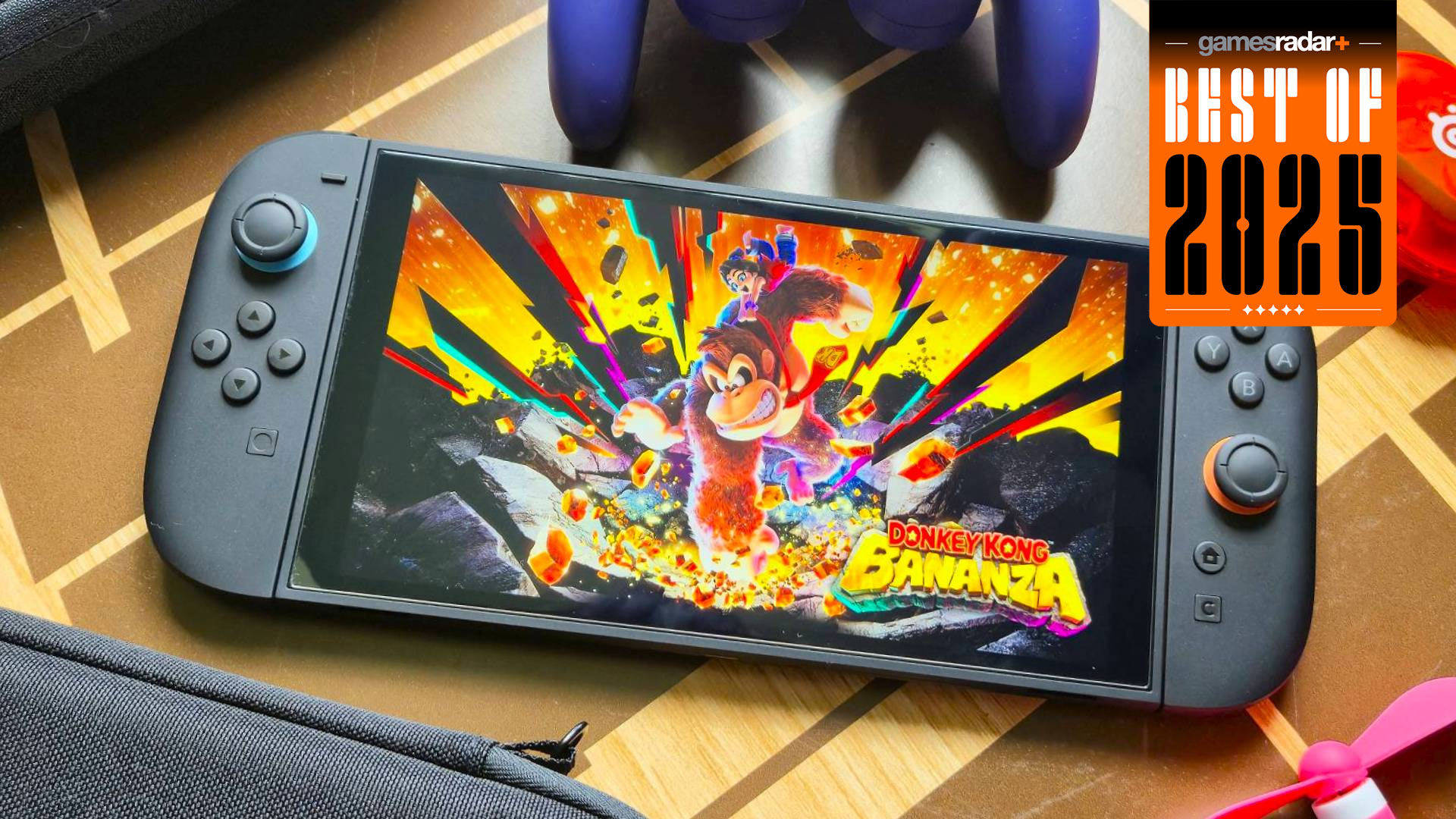 The Nintendo Switch 2 playing Donkey Kong: Bananza and surrounded by accessories on a wooden table