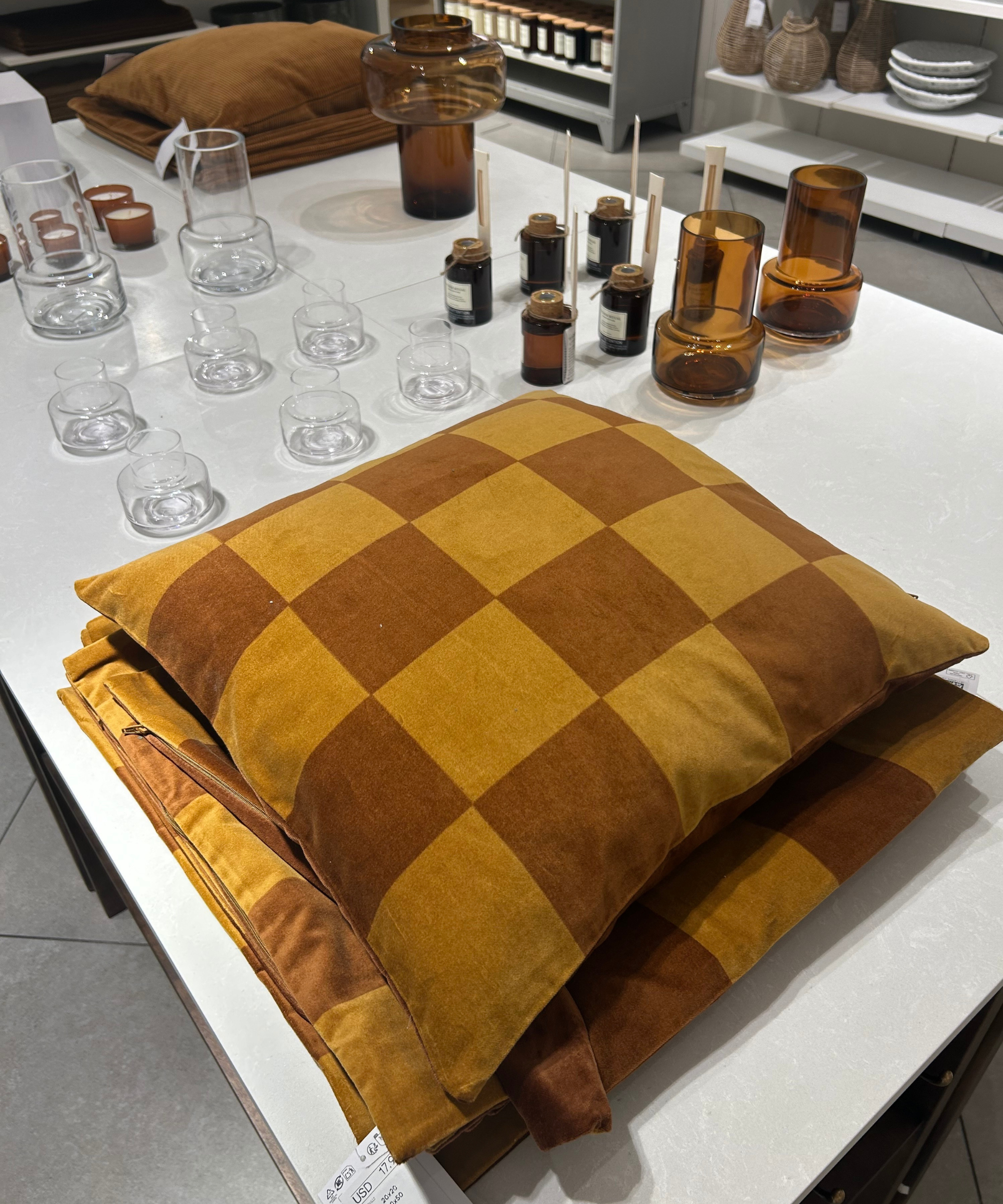 a checker printed pillow sitting on a table with glassware