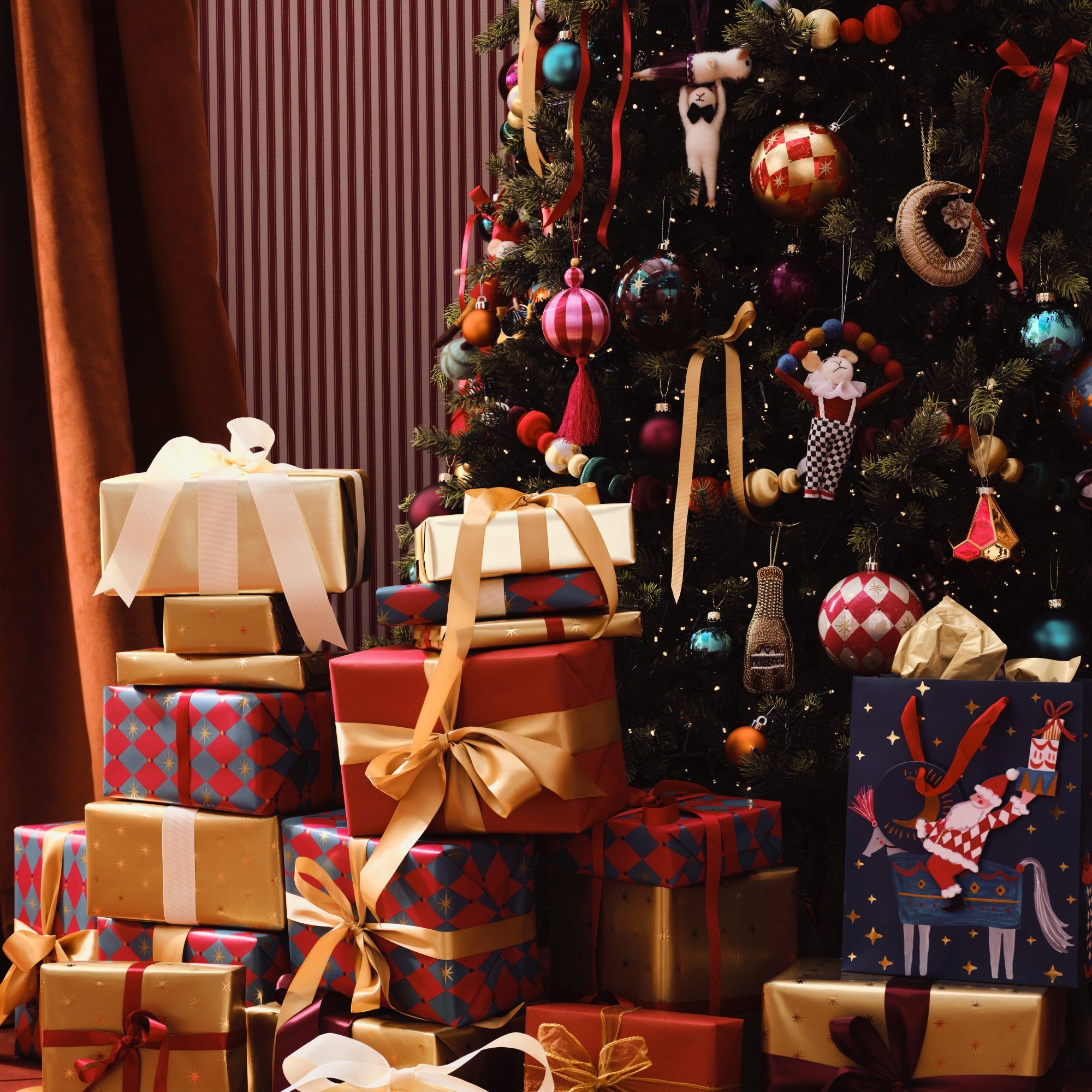 A Christmas tree with a pile of presents, decorated with decorations from the John Lewis Enchanted Tales range