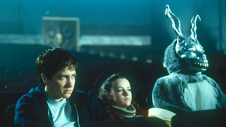  a boy and a girl sitting with someone in a weird rabbit costume