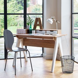 home office area with wooden desk with chair lamp book and window