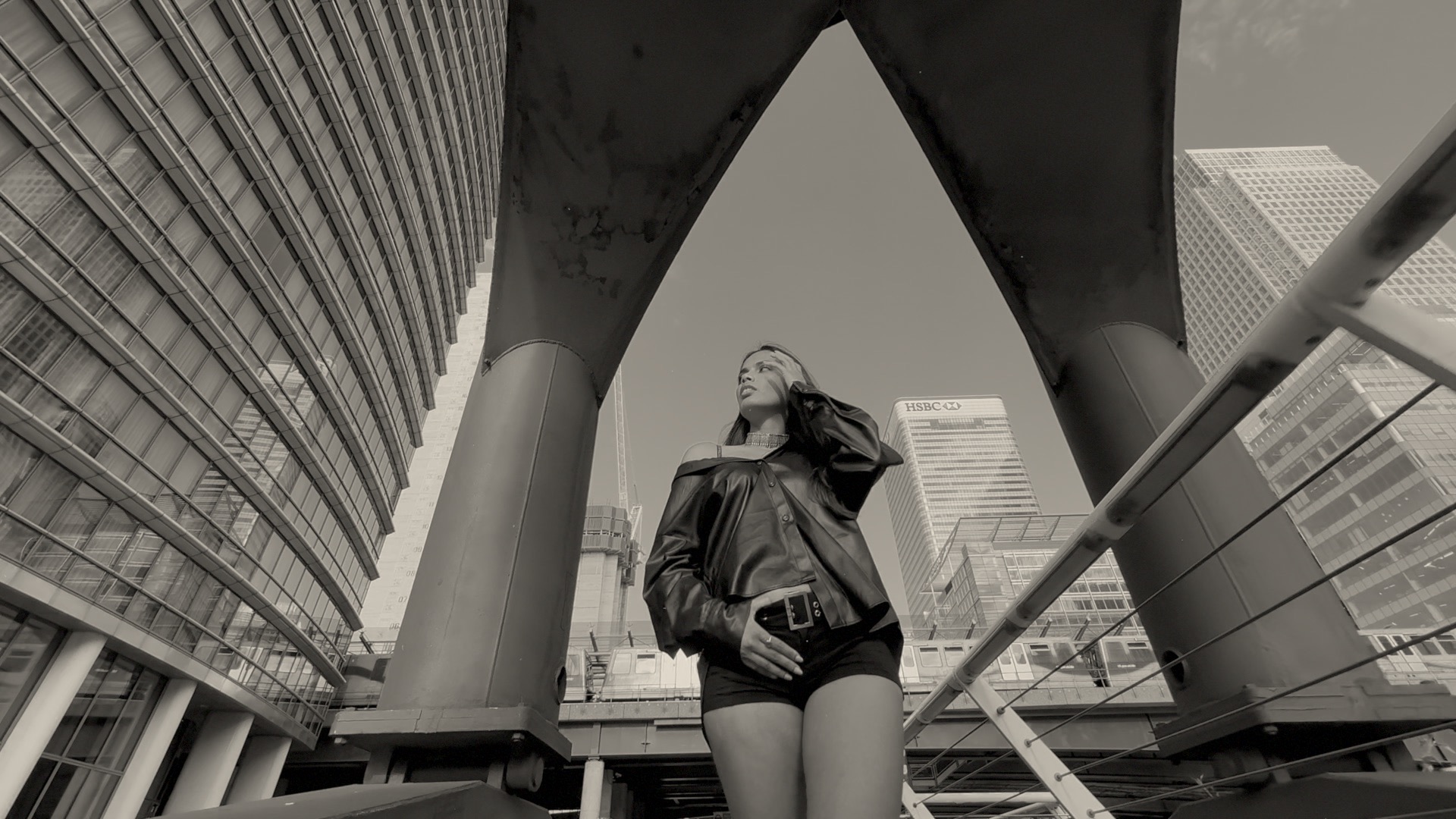 Low-angle frame from a view clip showing a model walking below a large steel crane