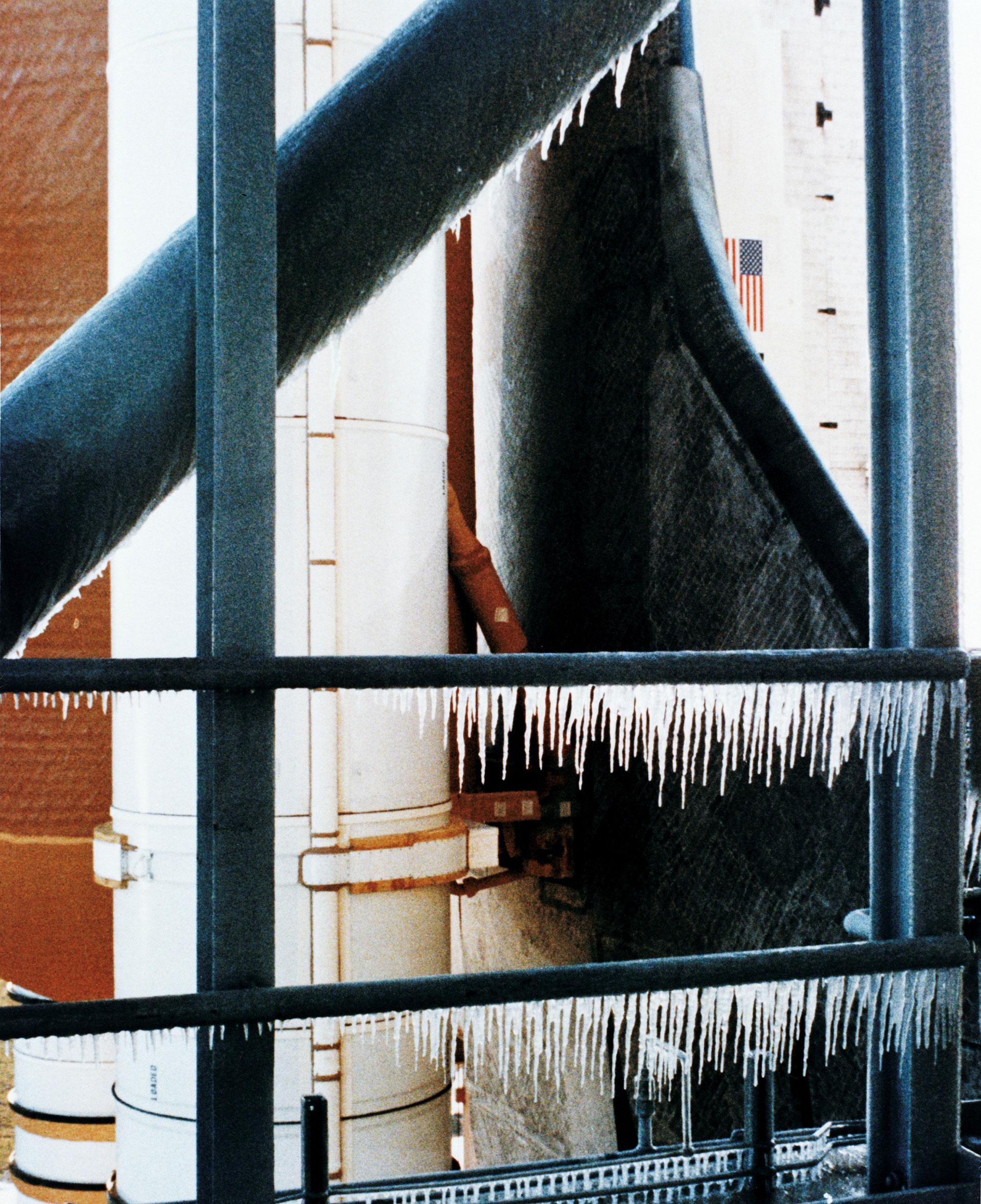 icicles hang from a metal railing in front of a space shuttle
