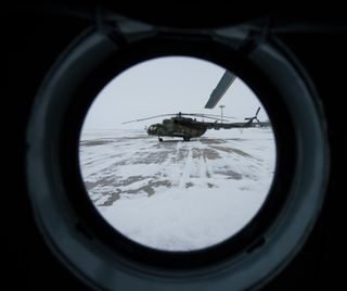 A Russian MI-8 helicopter is seen through the window of another helicopter at the Karanganda Airport shortly after poor weather forced the fleet of 12 helicopters to turn around from their flight to Zhezkazgan, Kazakhstan where they were to have pre-stage