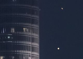 The rings of Saturn glide above Jupiter as the two planets pass near Burj Khalifa, the world's tallest building.