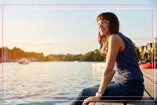 Happy woman sitting by a lake