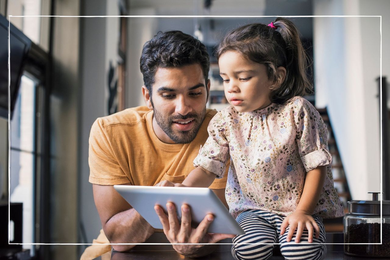 Millennial dad looking at an iPad with young daughter