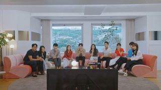 a group of people sit on pink couches while staring at a tv, in the korean show 'pink lie'