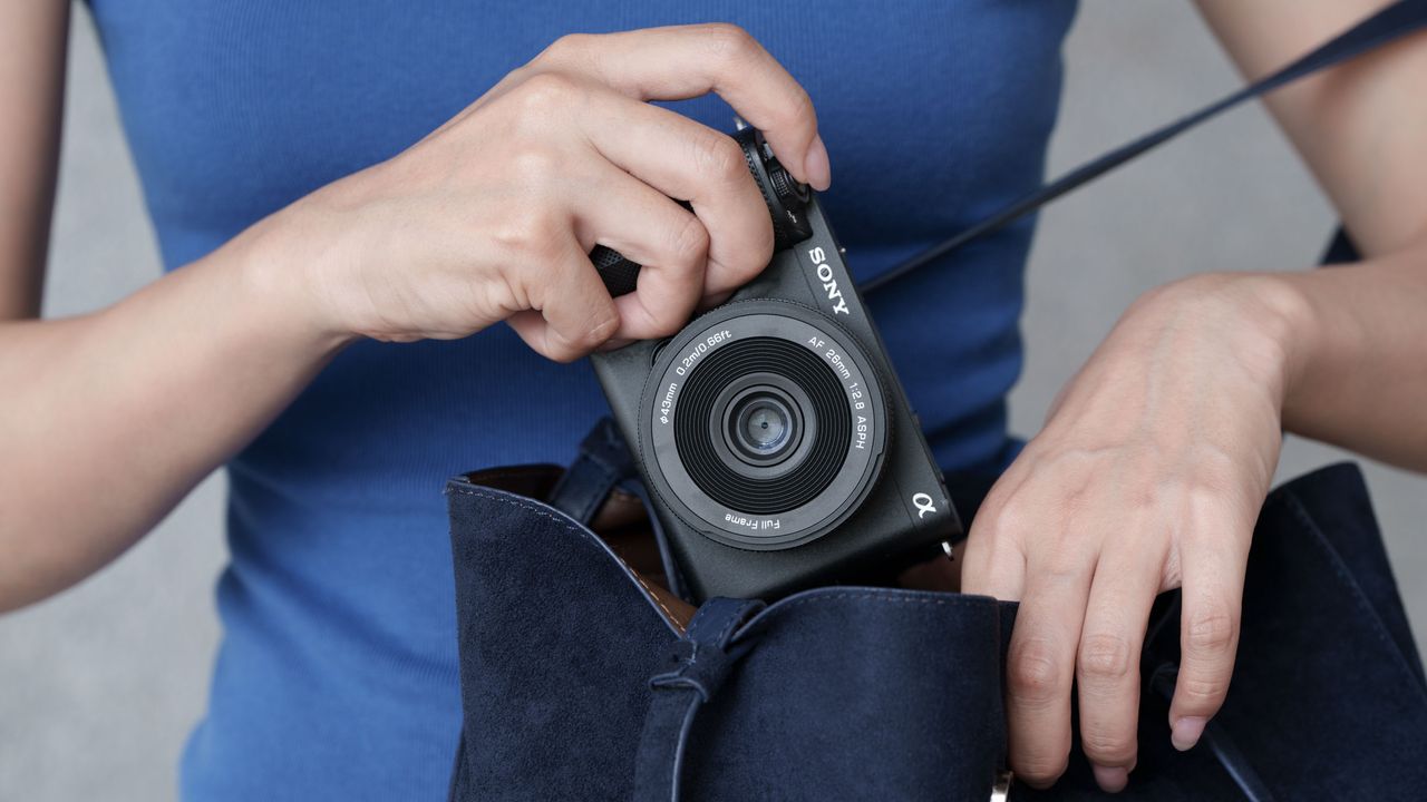 Viltrox AF 26mm F2.8 EVO lens attached to a Sony camera, woman is pulling it out of her handbag