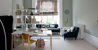 Rectangular living room divided by a open bookcase with a desk and chair