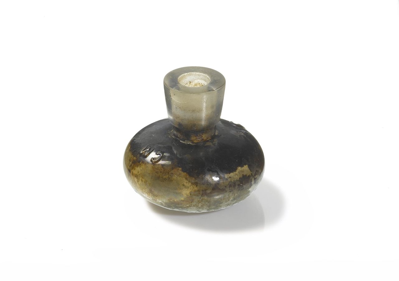A mid-19th to early-20th century glass inkwell. C and M are probably the initials of the retailer.