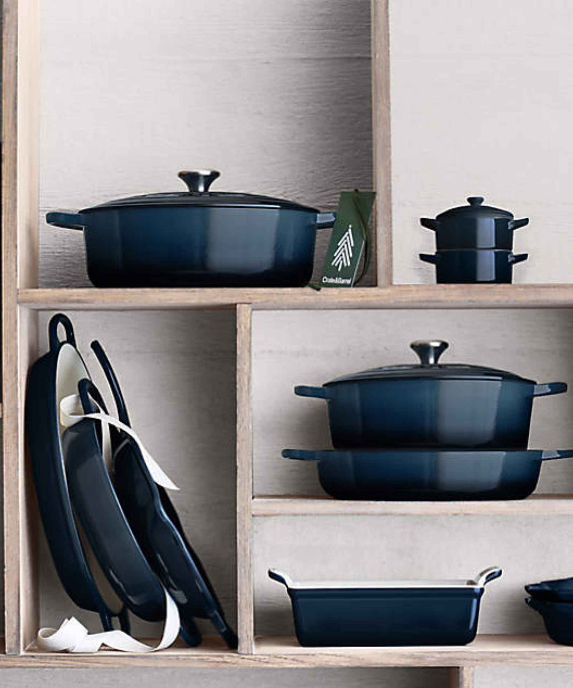 Deep blue Le Creuset cookware on wood shelf
