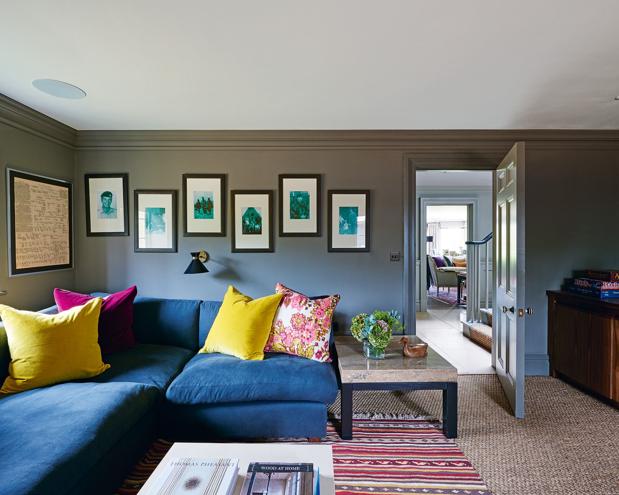Grey living room ideas with a large blue sofa, yellow and pink cushions and gallery wall.
