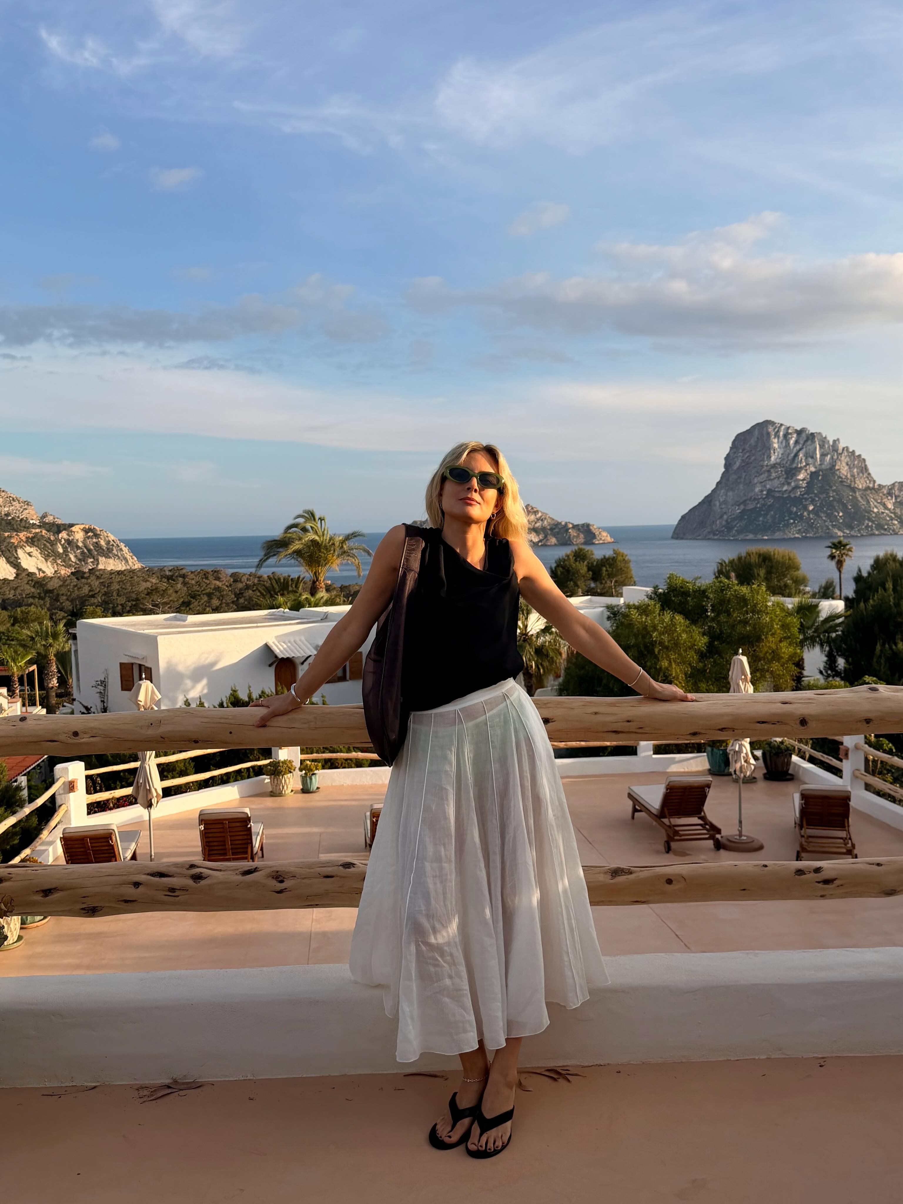 Woman in a black top, white poplin skirt and black thong sandals.