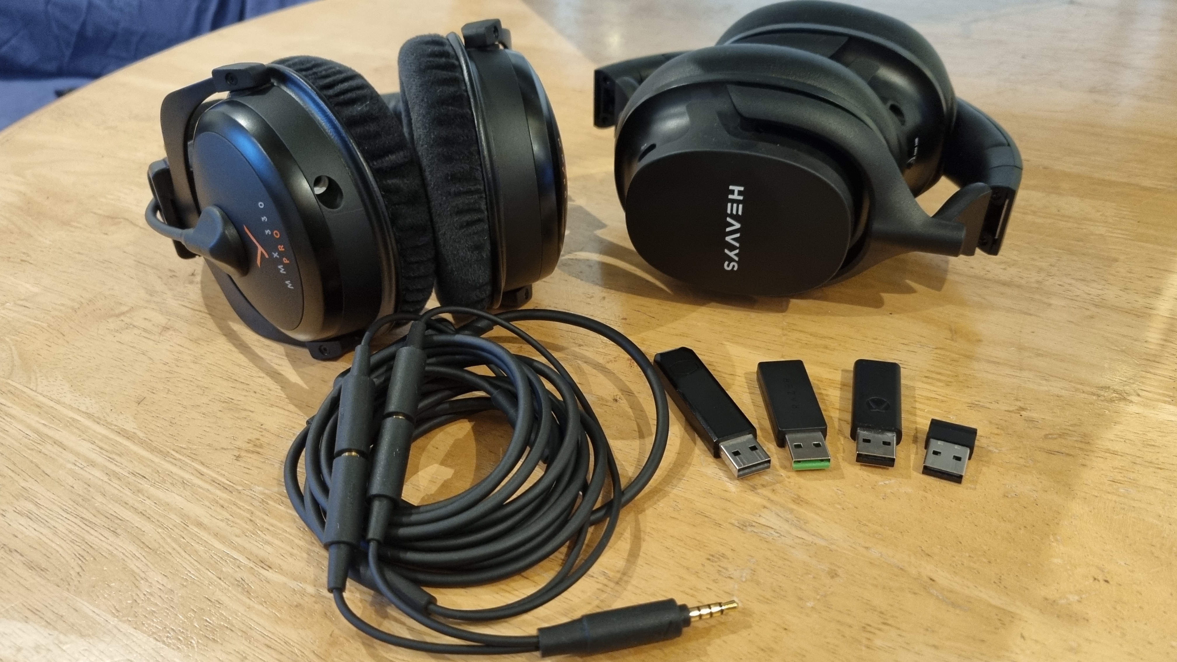 Two gaming headsets with a 3.5 mm jack to jack cable and various wireless dongles.