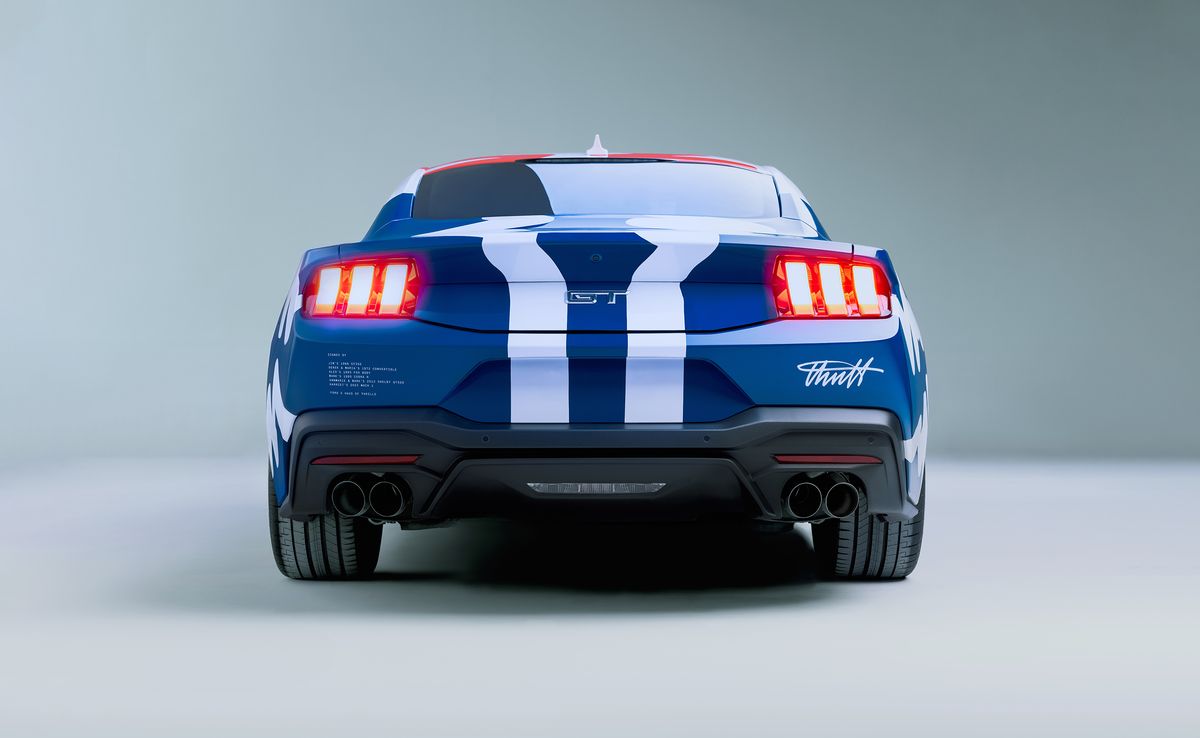 Photograph of the 60th year anniversary celebratory Mustang collaboration with Haus of Thrills. Rear view of white Mustang in a bright blue with two vertical white lines running through the middle.