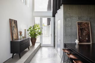 A modern entryway with neutral decor, cement walls, and grey stone flooring