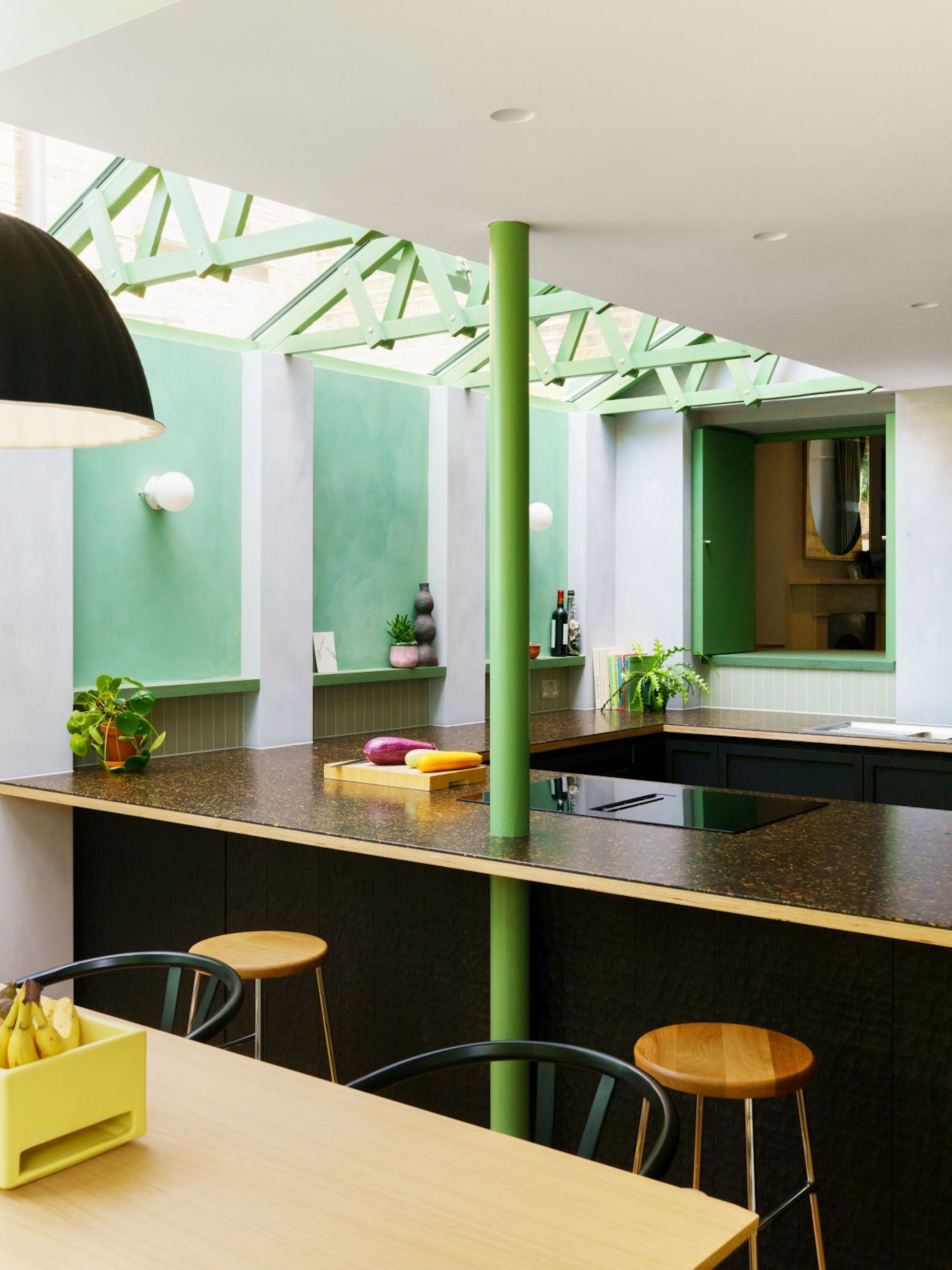 A modern, white and green kitchen and dining space with minimalistic style furniture and storage.