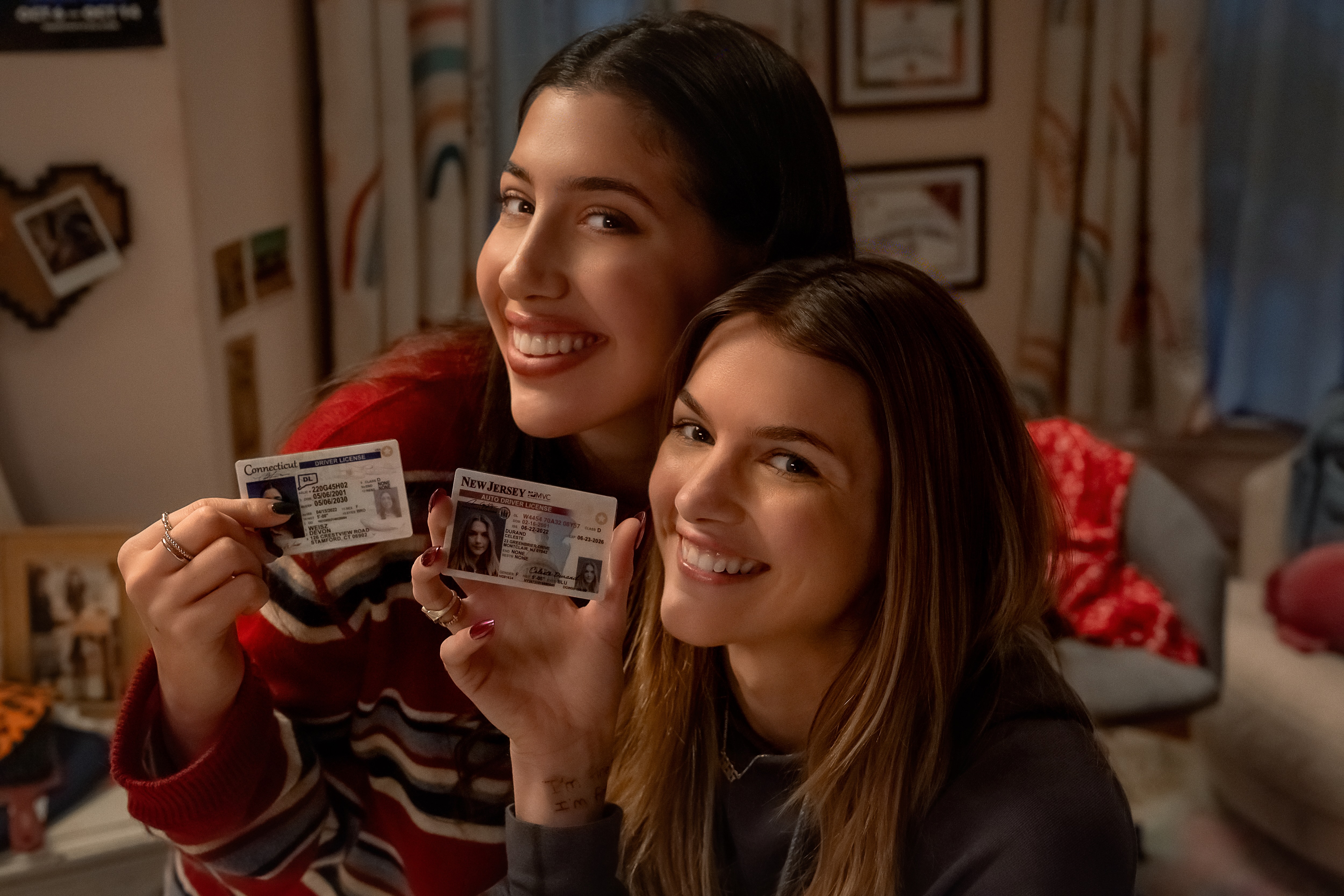 Two girls (Sadie Sandler as Devon and Chloe East as Celeste) post with their student IDs in Netflix's 'Roommates'.